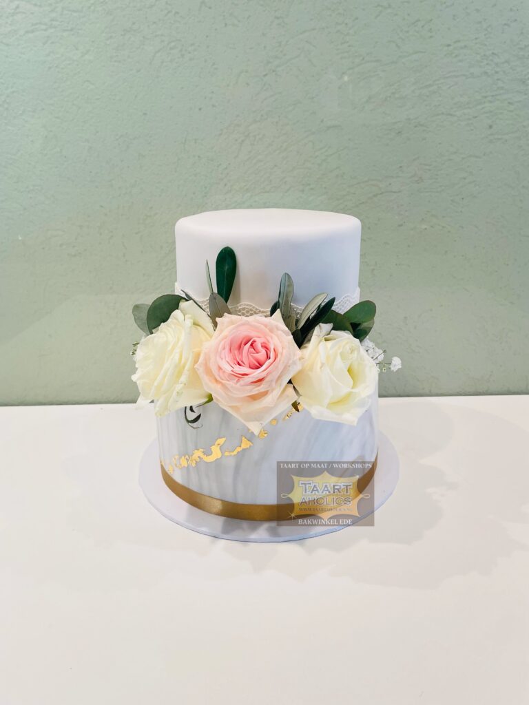Tweelaagse bruidstaart in wit en marmer met een gouden band en verse witte en roze rozen