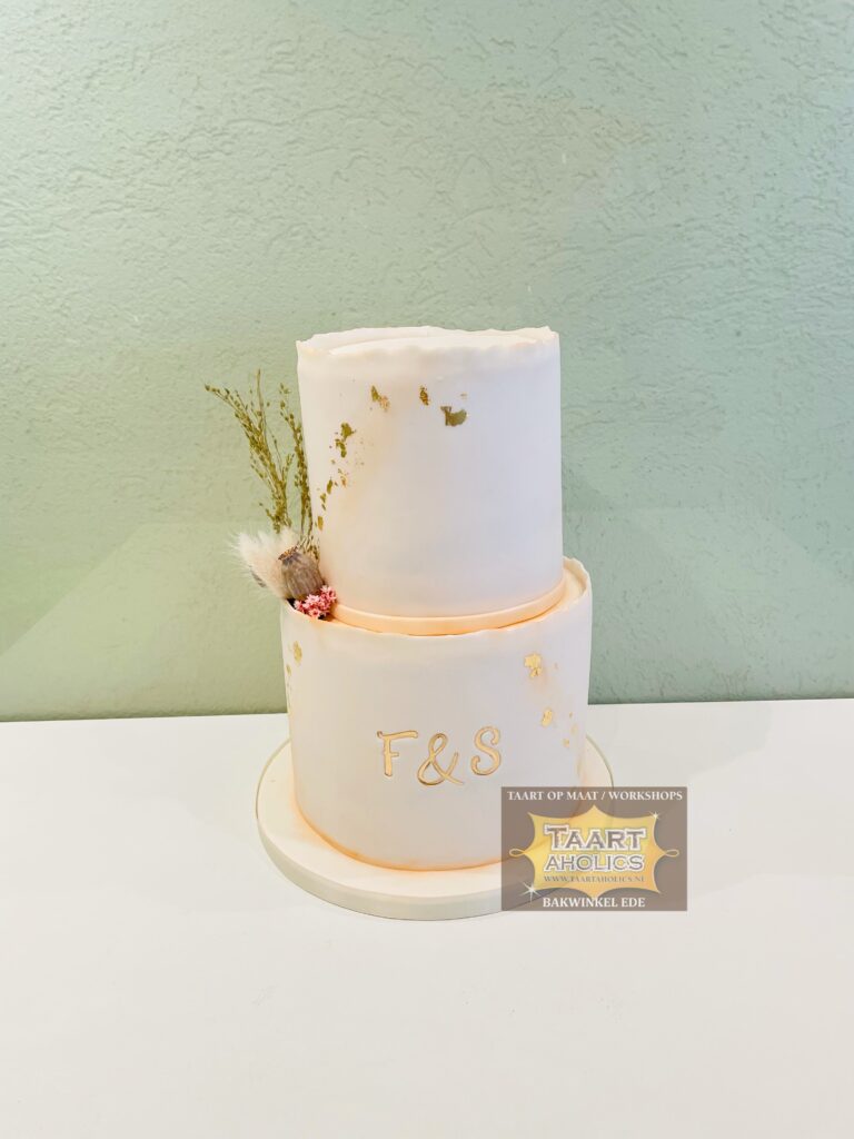 Tweelaagse bruidstaart in zachtroze met bladgoud, droogbloemen en de initialen F en S