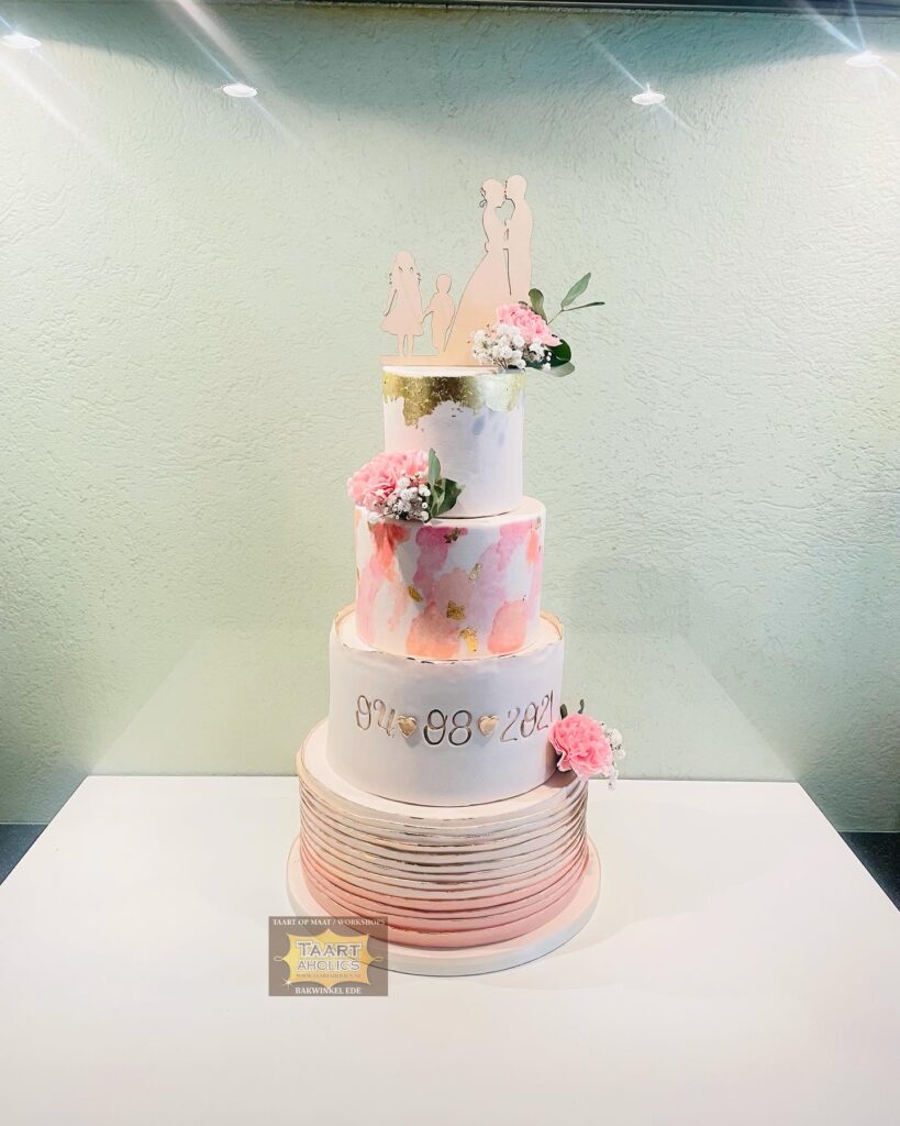 Vierlaagse bruidstaart met roze aquarelwerk, bladgoud, de trouwdatum en een silhouettopper van het bruidspaar